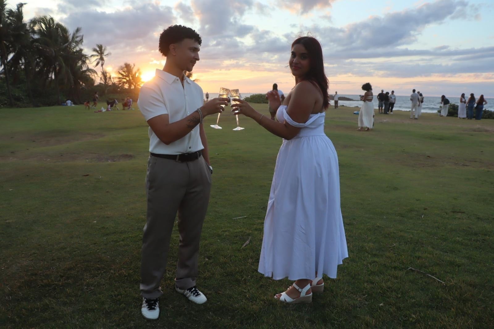 Pareja celebra su historia bajo un cielo de atardecer junto al mar